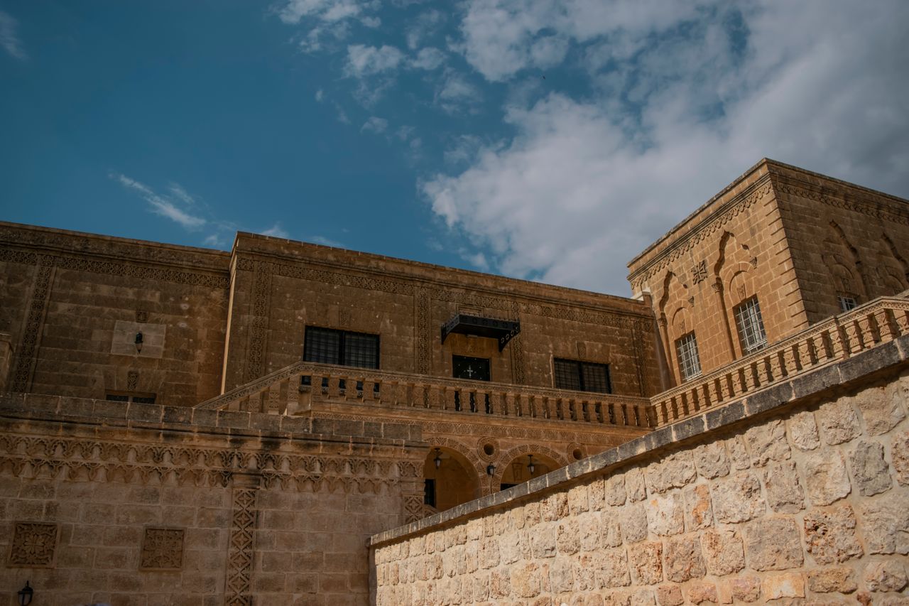 hero-img-02 Beautiful historic stone building in Midyat, showcasing intricate designs and clear skies.